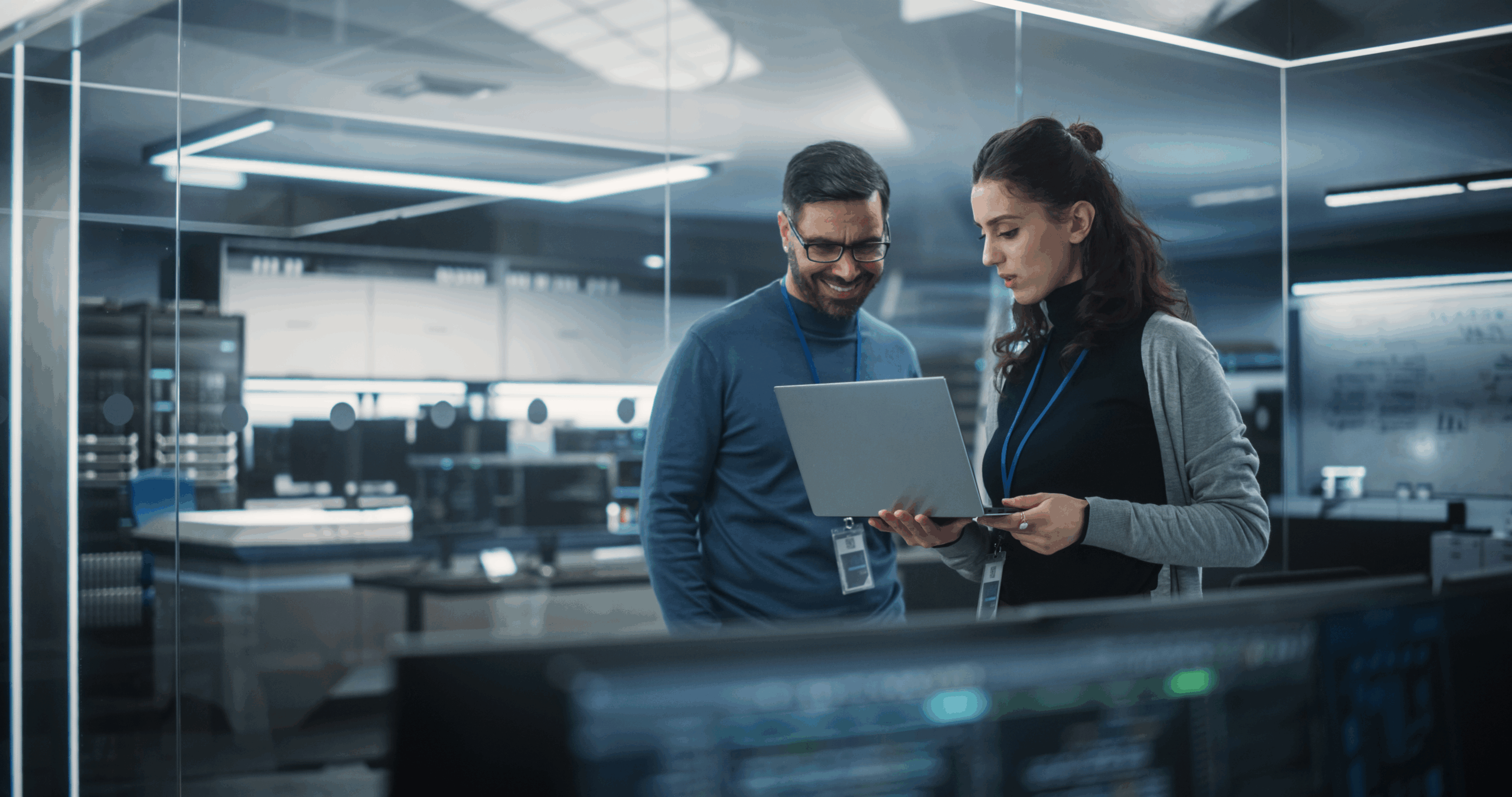 Data Security Professionals standing together looking at a laptop in a high-tech office.